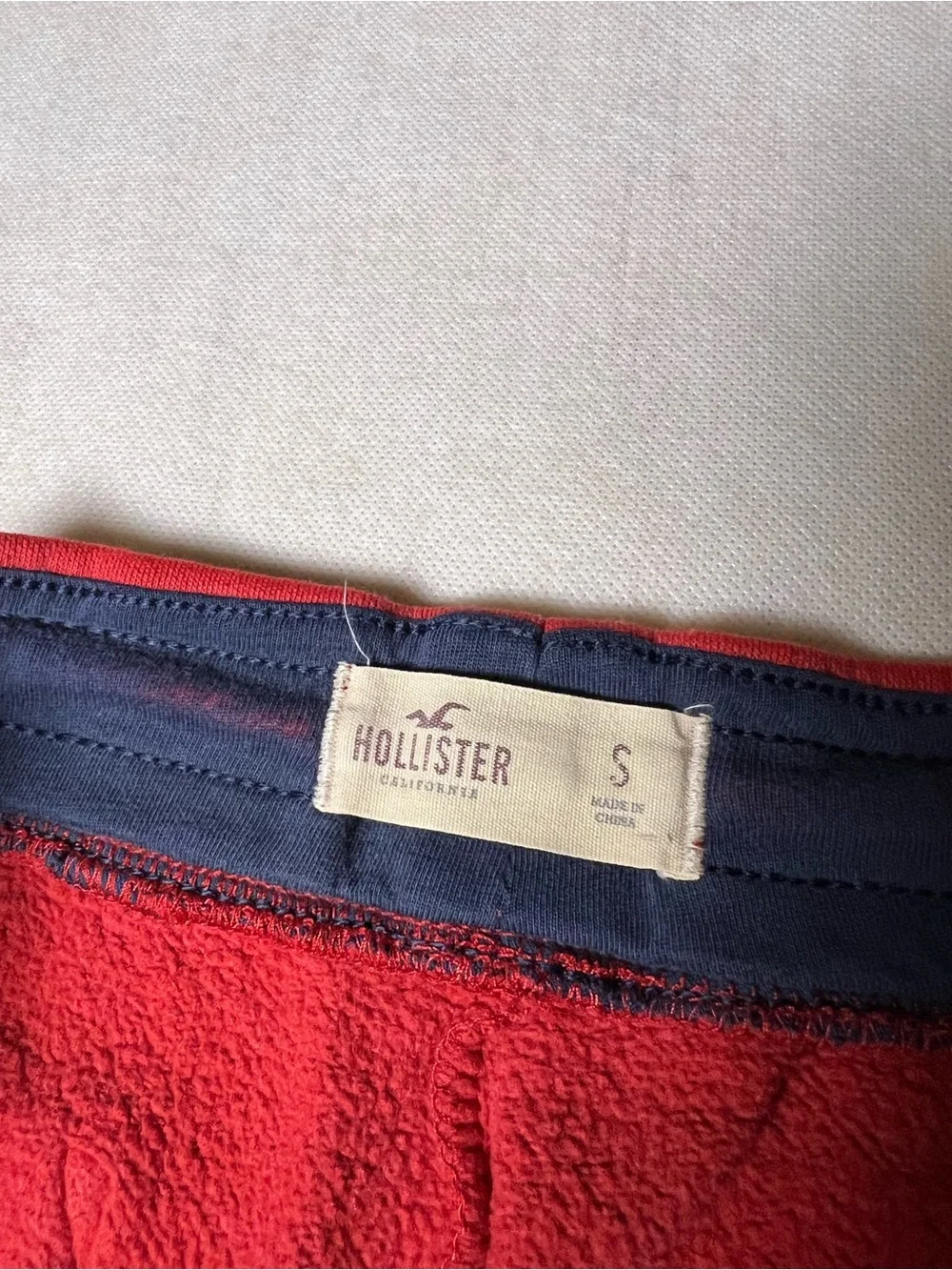 Hollister Co. red sweatpants with white vertical text reading 'HOLLISTER'